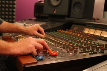 Mix engineer pushing faders on a mixing console